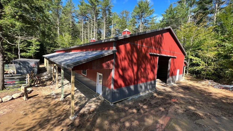 A red barn with a porch in the middle of a forest.
