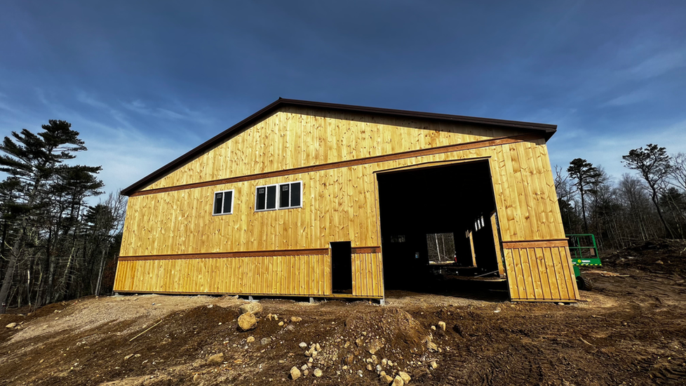 A large wooden building is being built in the middle of a dirt field.