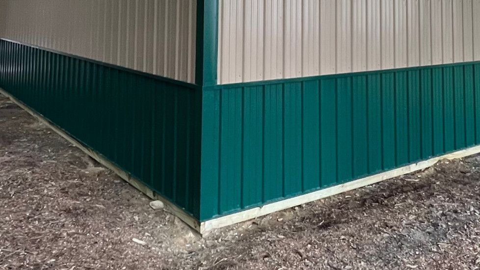 The corner of a building with green siding and a white wall.
