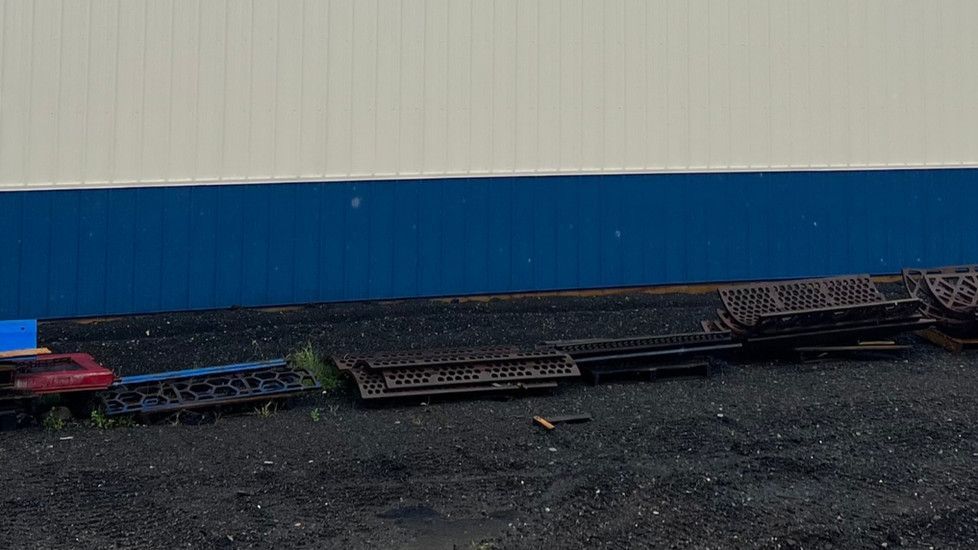 A train is sitting on the ground in front of a blue and white wall.