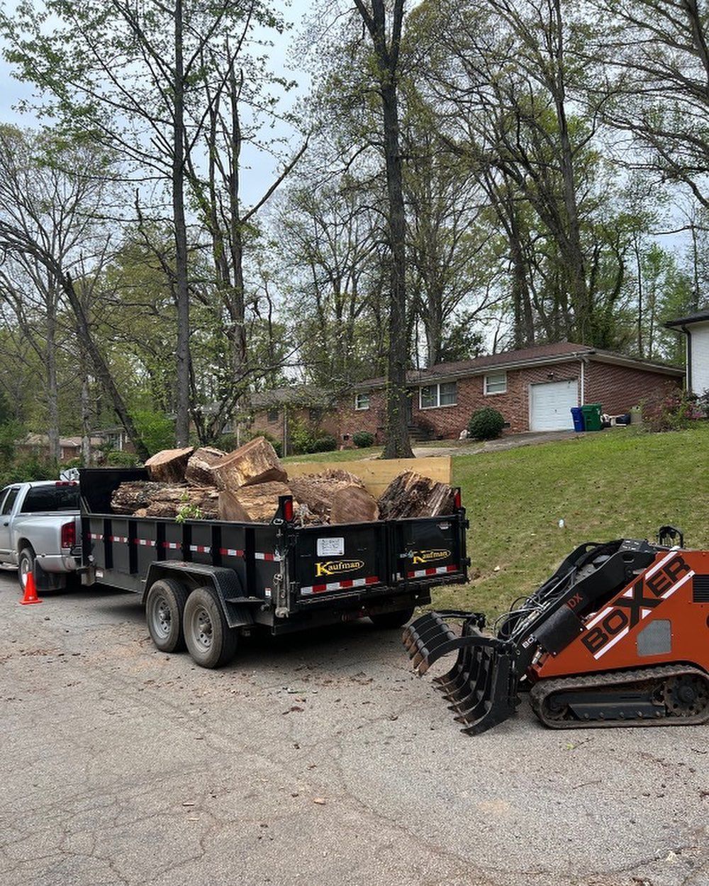 A dump truck with a trailer full of rocks is parked in a driveway next to a bulldozer.