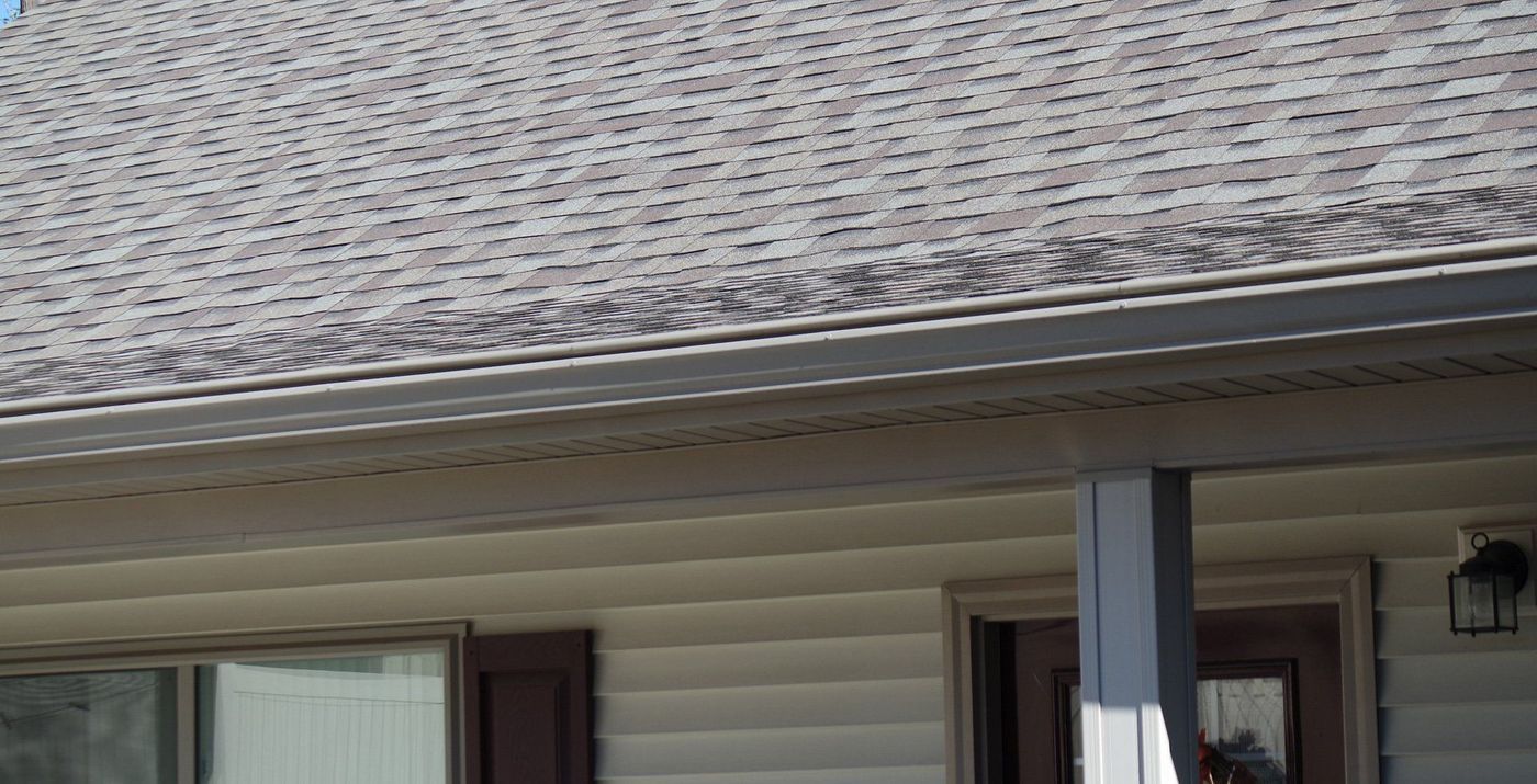 Roof with gutters and siding on a house. Brown and tan colors.