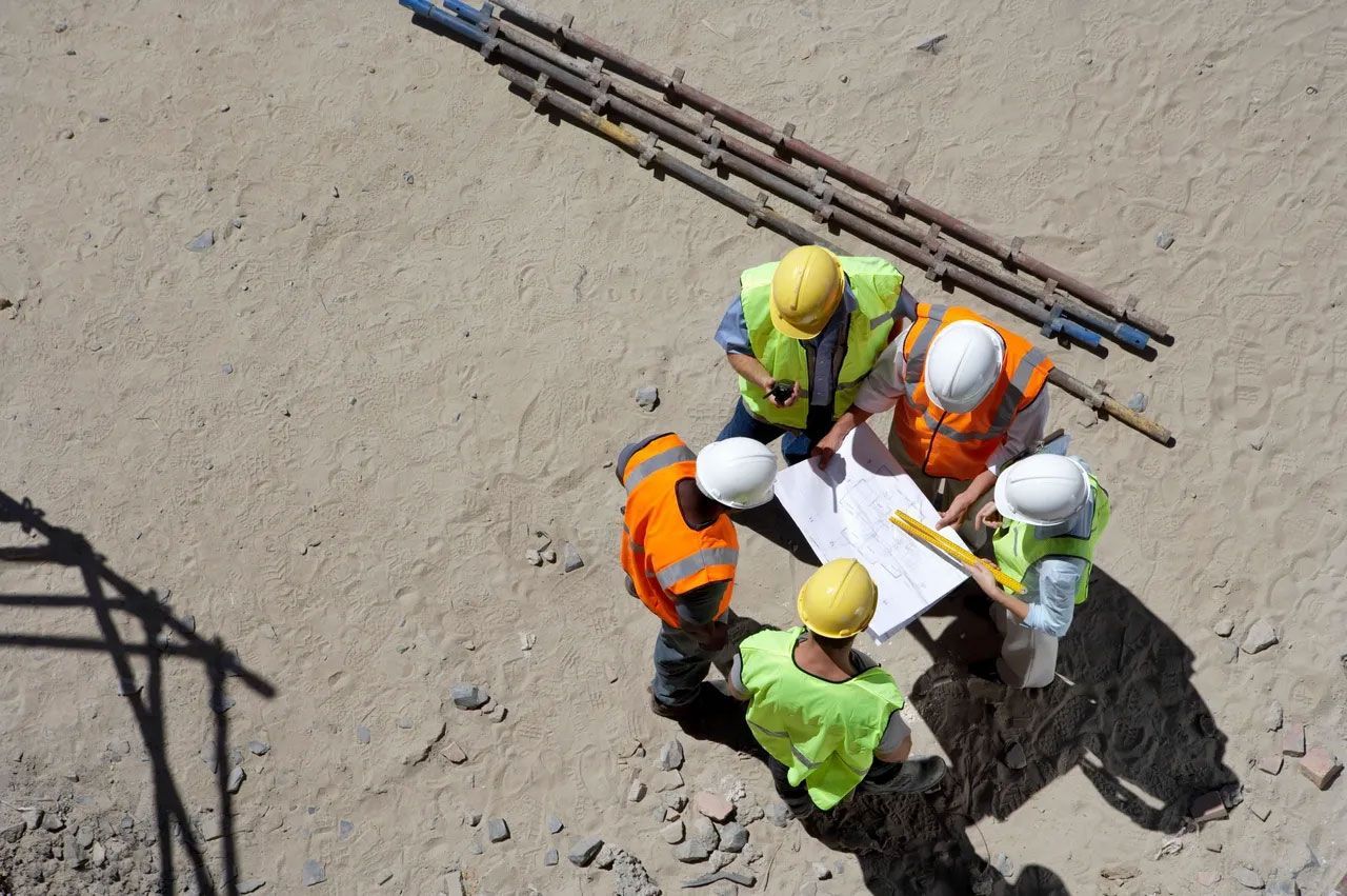A group of construction workers are looking at a blueprint on a construction site