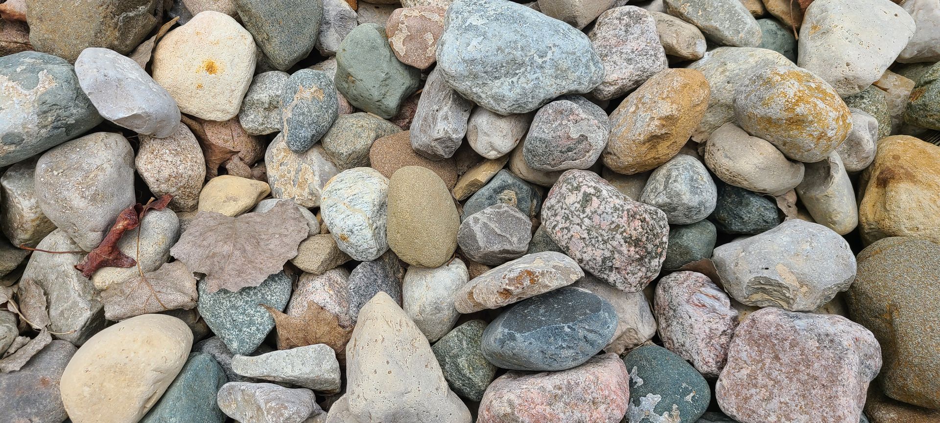 A close-up of assorted gray, tan, and pink pebbles filling the frame.