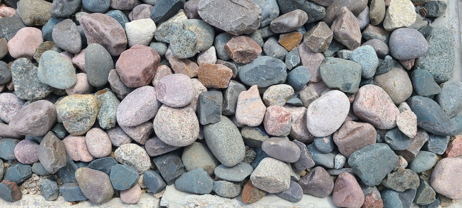 Close-up of multicolored smooth pebbles and rocks covering the ground.