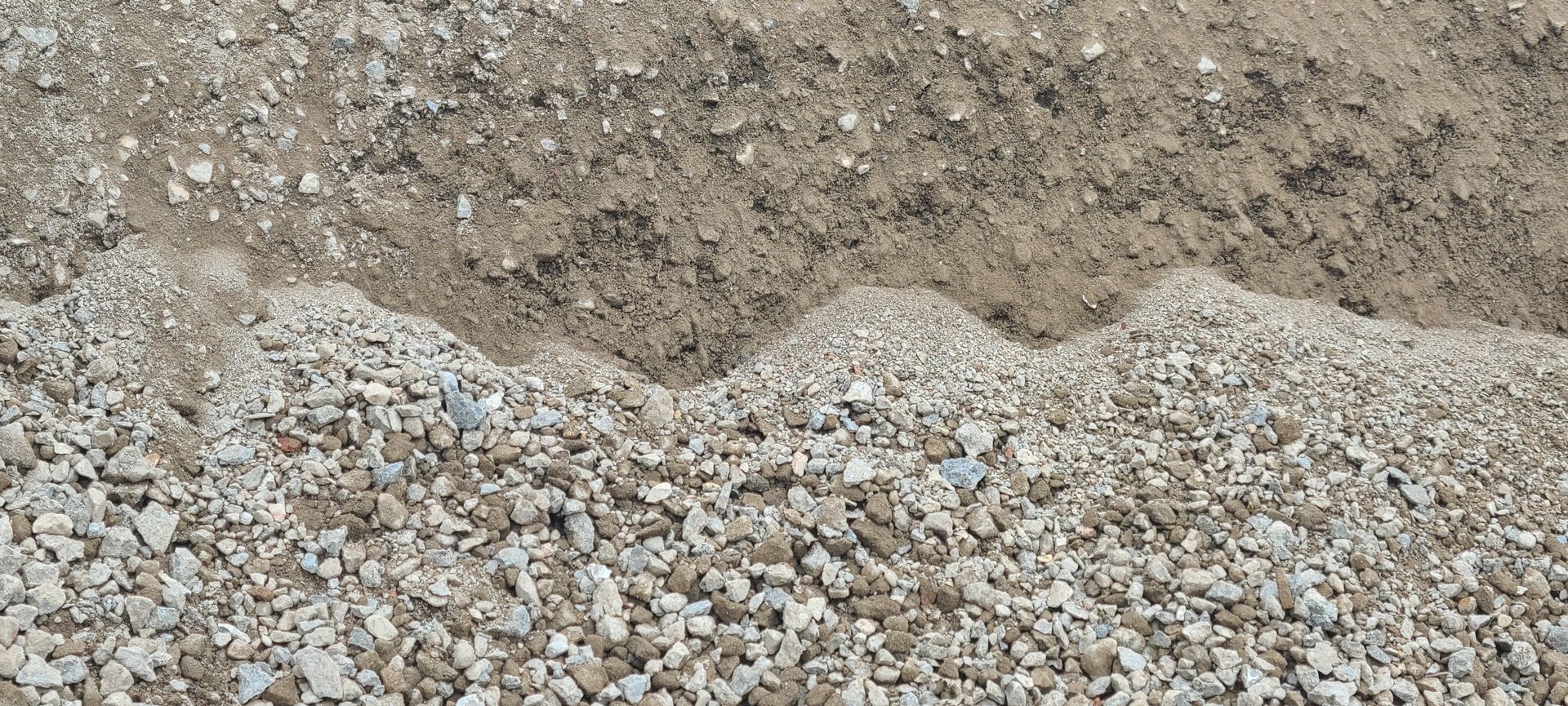 Pile of gray gravel mixed with brown dirt on the ground