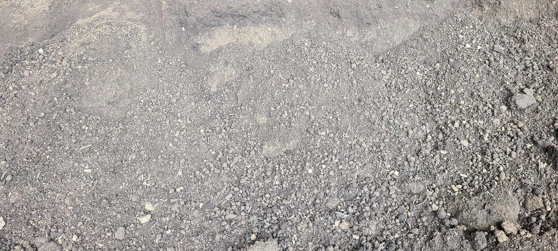 Close-up of a rough gray gravel surface with scattered small stones and light patches.