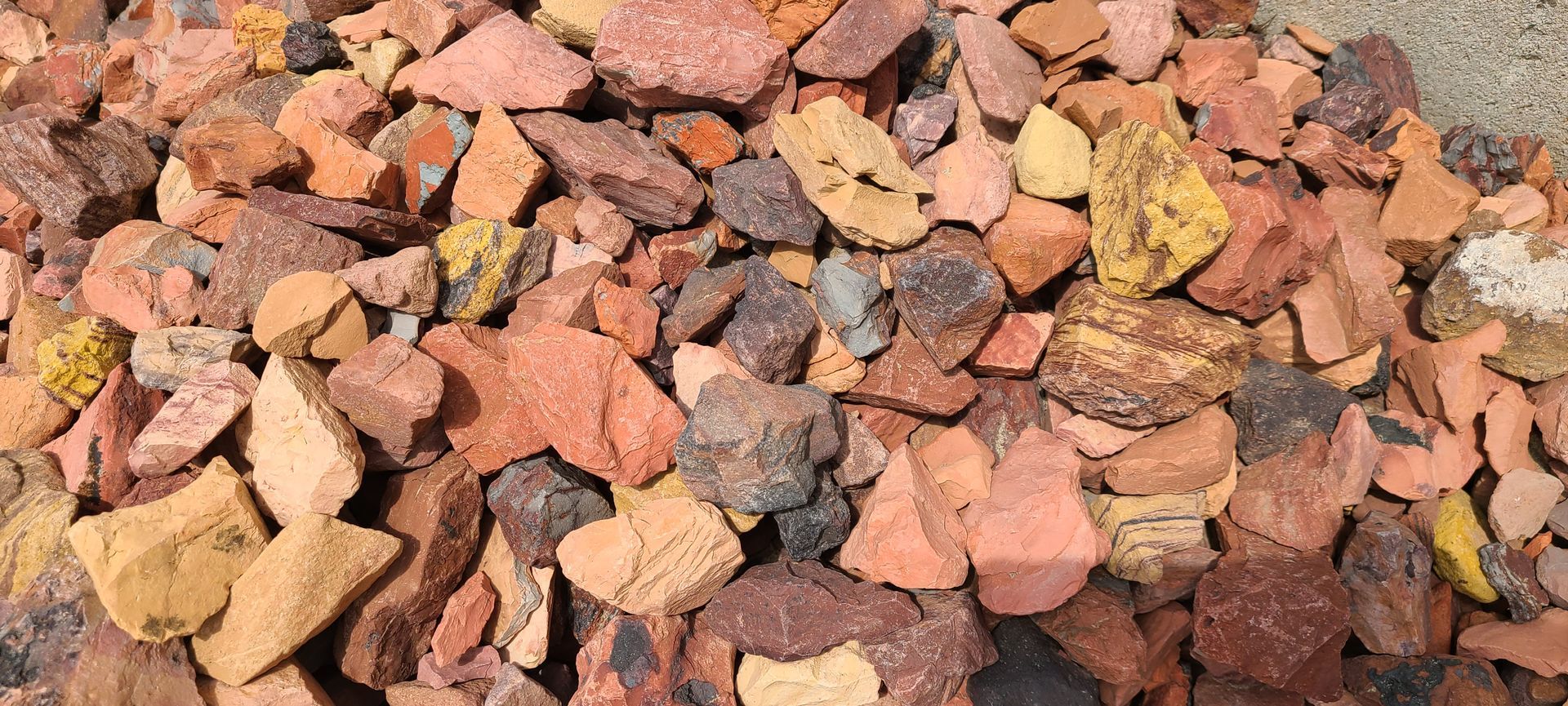 Pile of multicolored rocks and gravel in shades of red, brown, yellow, and gray
