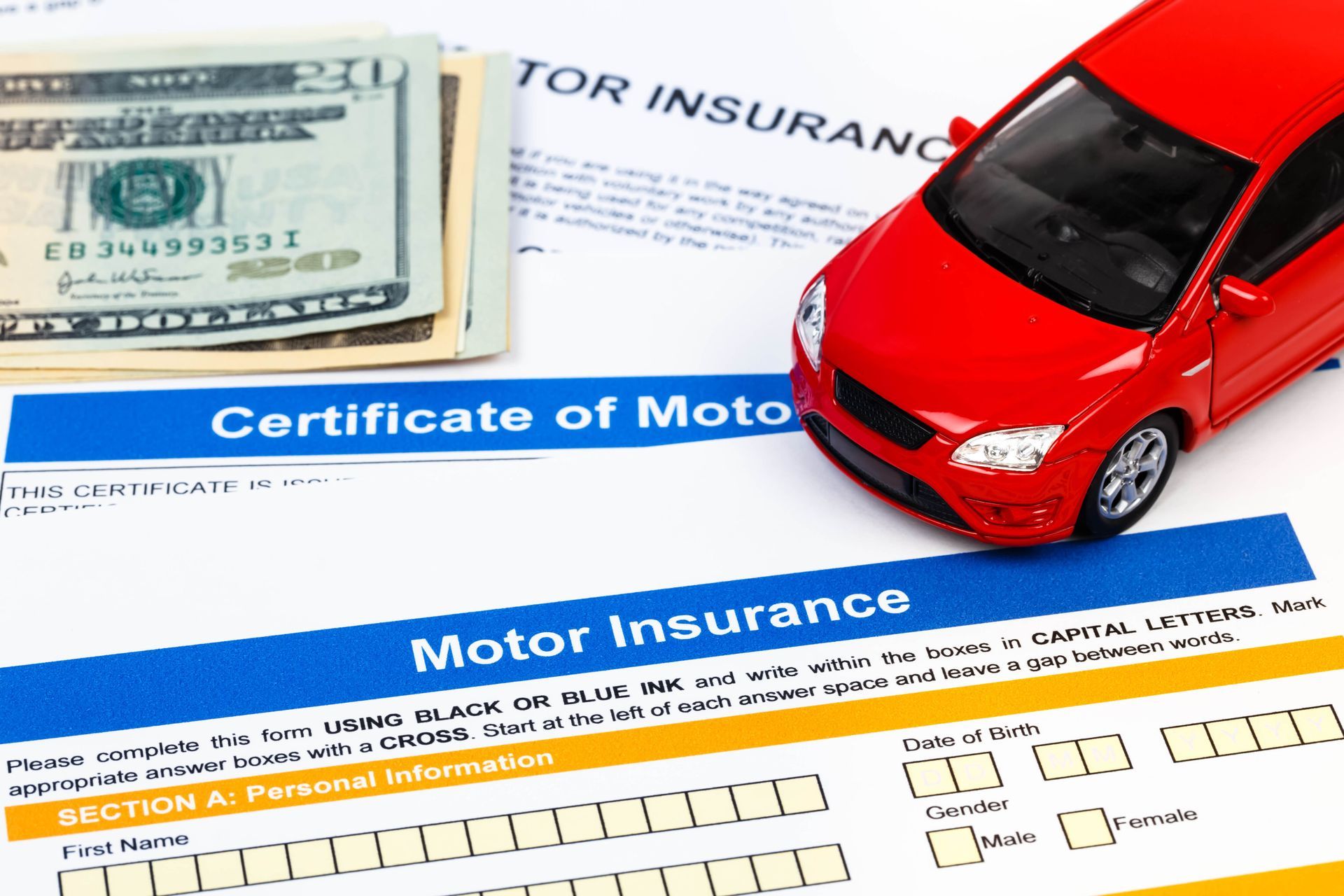 Red toy car, cash, and motor insurance paperwork on a white surface, signifying car insurance.