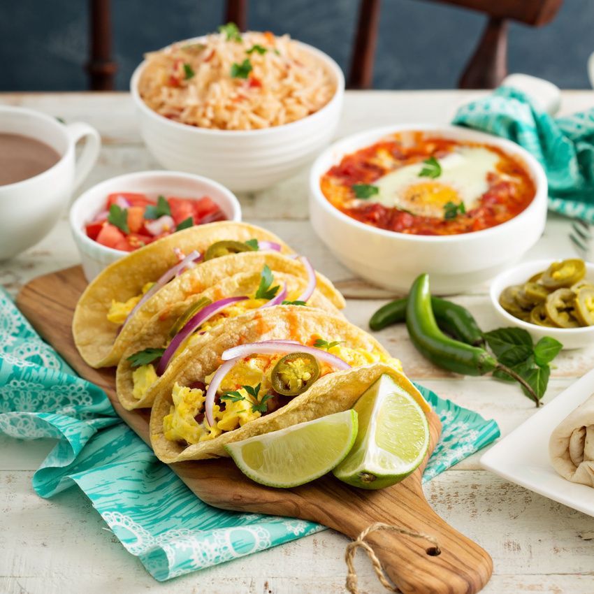 A wooden cutting board topped with tacos and lime slices