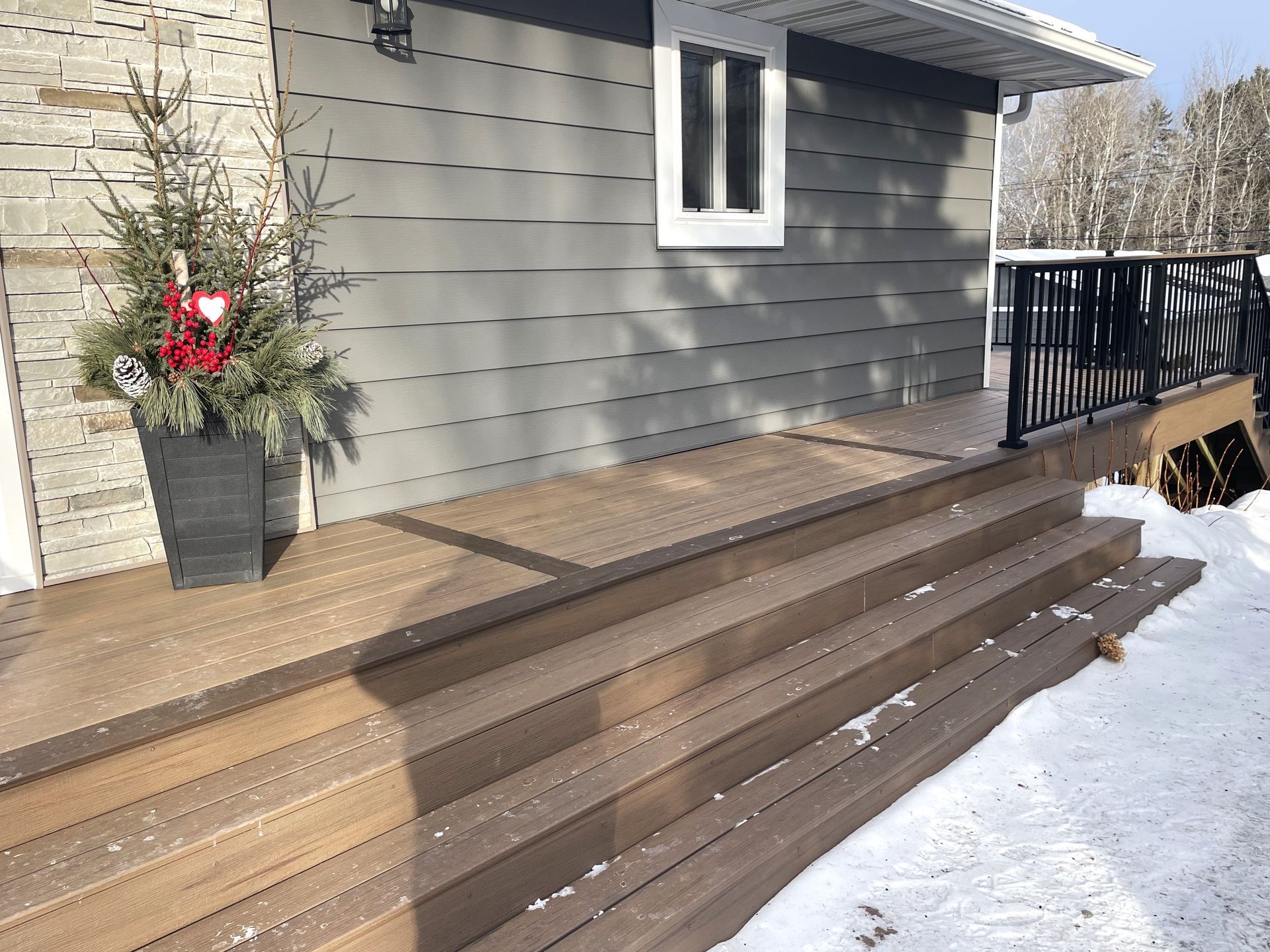 A house with a wooden porch and stairs in the snow.