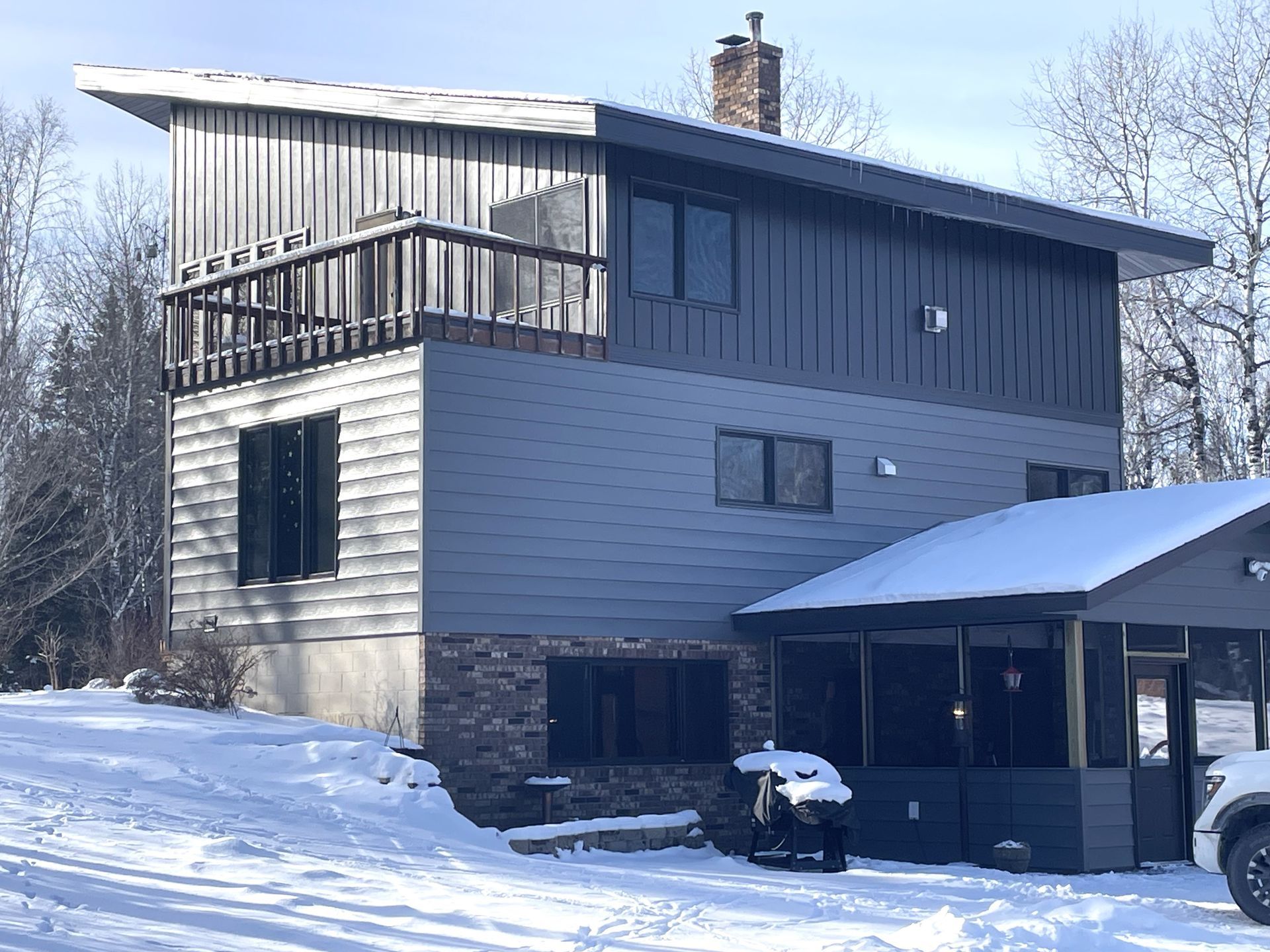 A house is covered in snow and a car is parked in front of it.