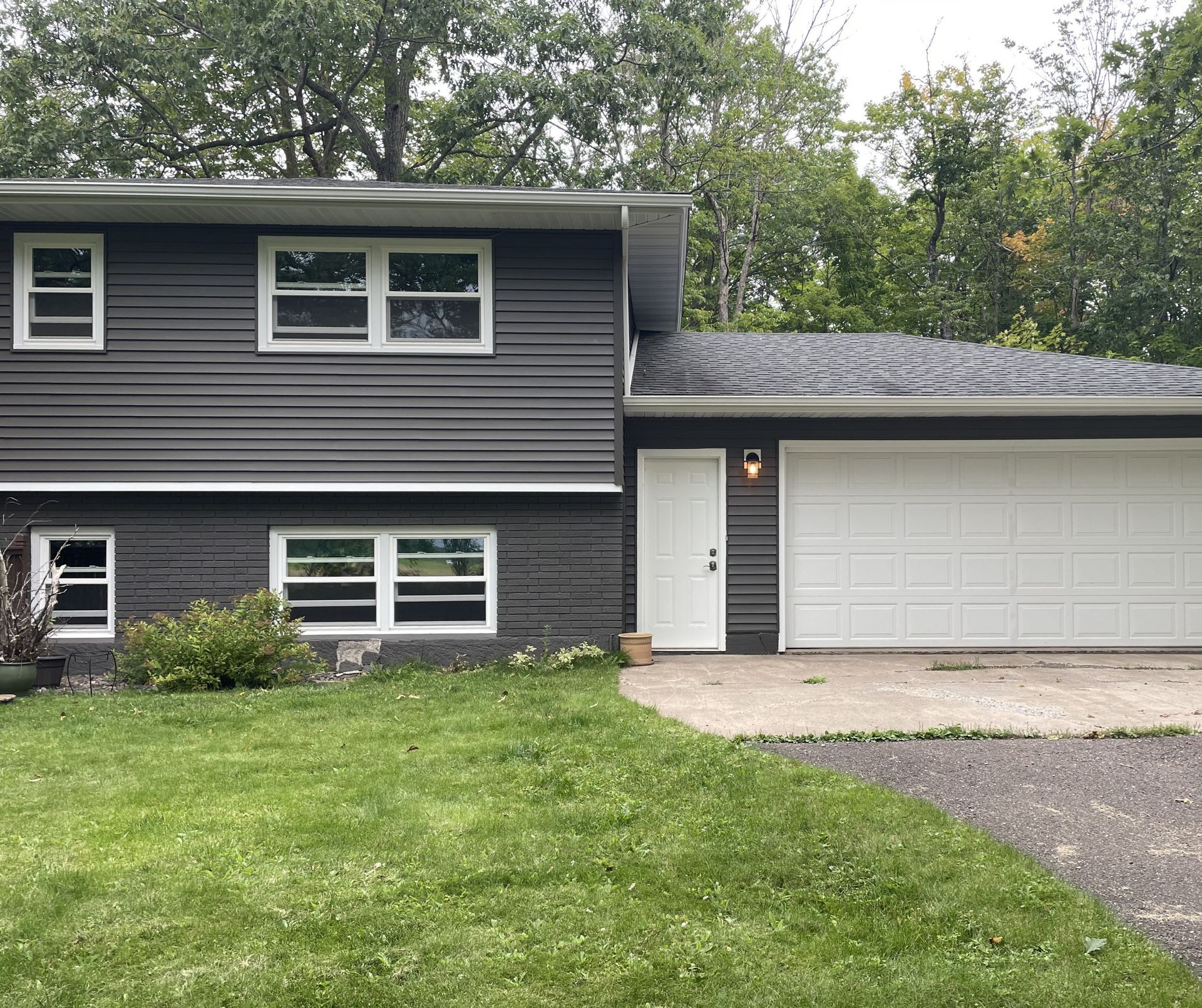 A gray house with a white garage door and a white door