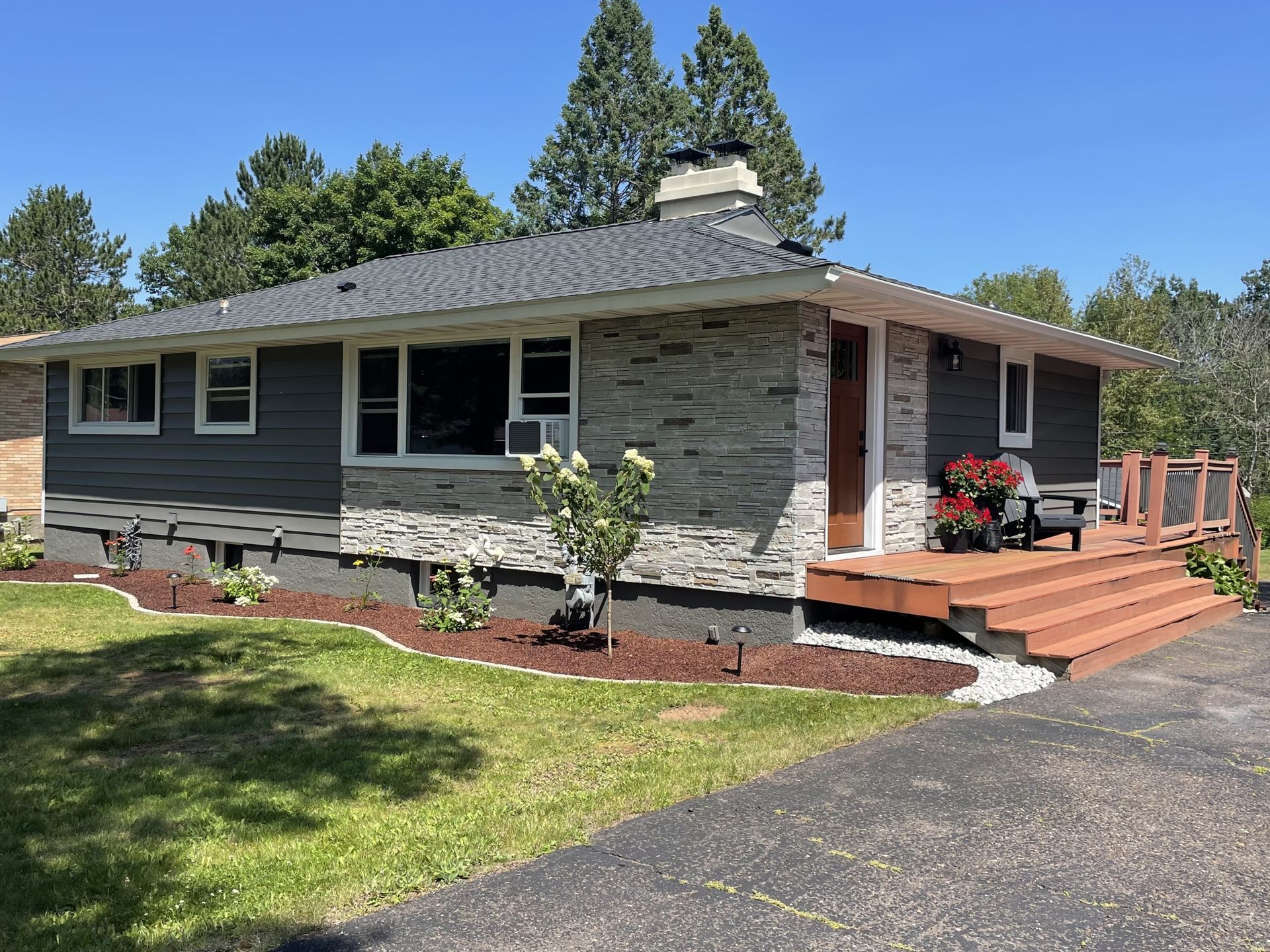 A brick house with a wooden deck and stairs in front of it.