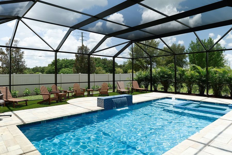 Pool area with blue water, lounge chairs, and a screened enclosure under a partly cloudy sky.
