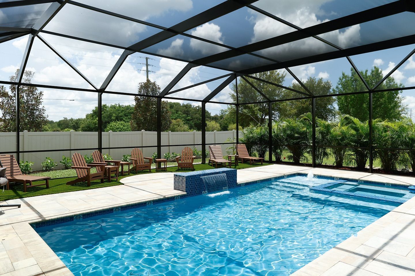 Swimming pool enclosed in a screen structure with seating area under a cloudy sky.