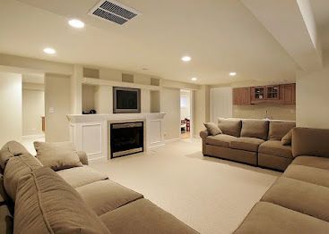 Spacious beige living room with sectional sofas, fireplace, recessed lighting, and a TV above the mantel