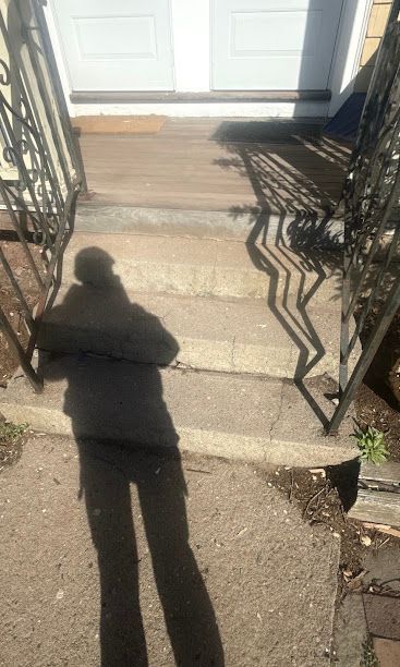 Shadow of a person on concrete steps leading to a white front door.
