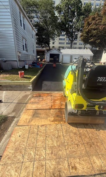 Wooden ramp leading to a driveway with a yellow utility vehicle parked on the right.