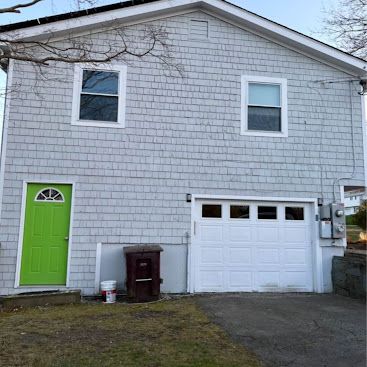 Gray house with a bright green side door and white garage door, front view.