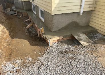 House foundation with exposed dirt and gravel during exterior construction work
