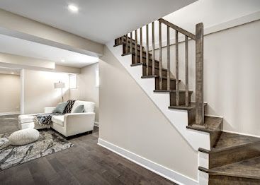 Living room with white sofa, rug, and staircase with dark wood steps and railing