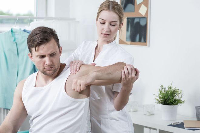 A healthcare professional examines a patient's arm in a medical setting.