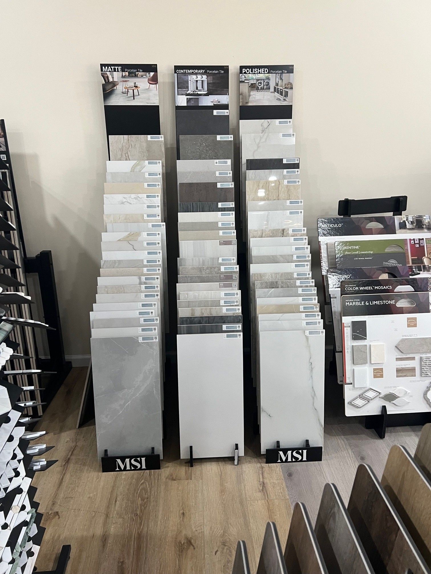 Three tall white brochure racks filled with pamphlets in a store or showroom.