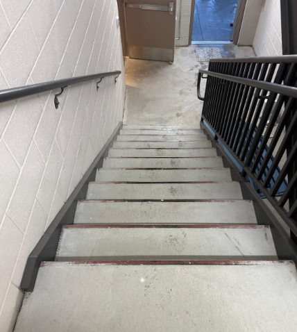 Indoor stairwell with white steps, black railings, and a doorway at the top