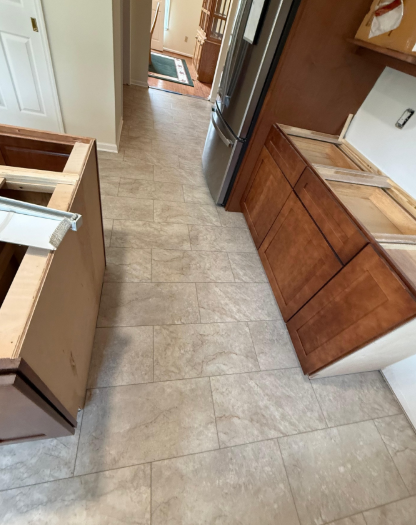 Kitchen with beige tile floor, wood cabinets, and a dishwasher along a narrow walkway.