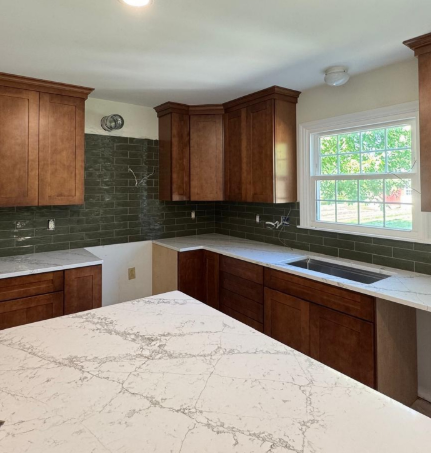 Bright kitchen with wood cabinets, white countertops, green tile backsplash, and a large window.
