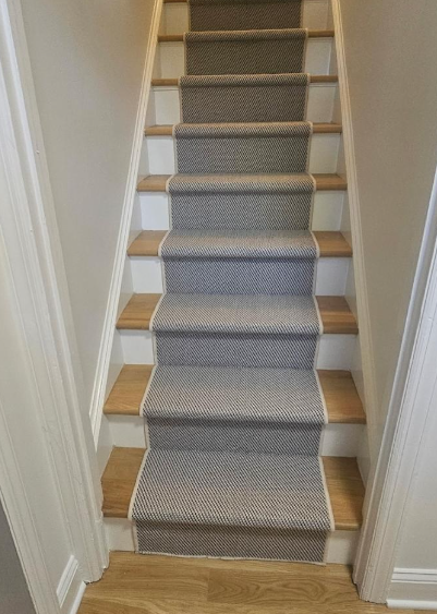 Carpeted staircase with gray runner and wooden steps in a narrow hallway