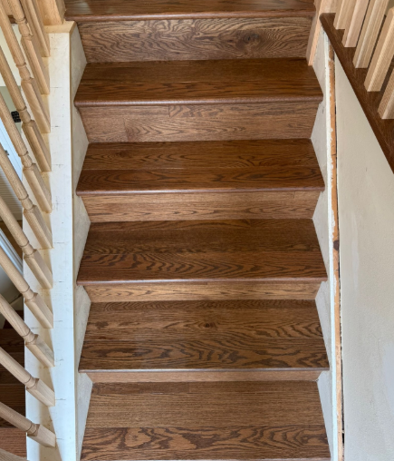 Wooden staircase with brown treads and white railings, viewed from above