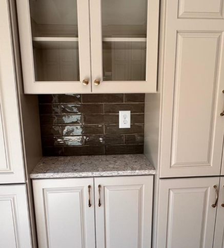 Kitchen cabinet nook with glass doors, dark tile backsplash, and granite countertop