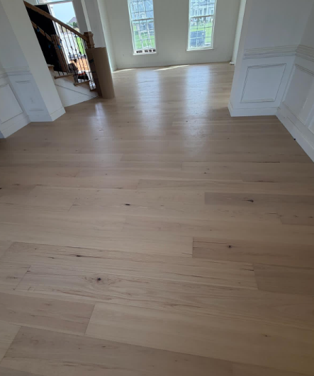 Empty light-wood floor in a bright room with tall windows and white walls