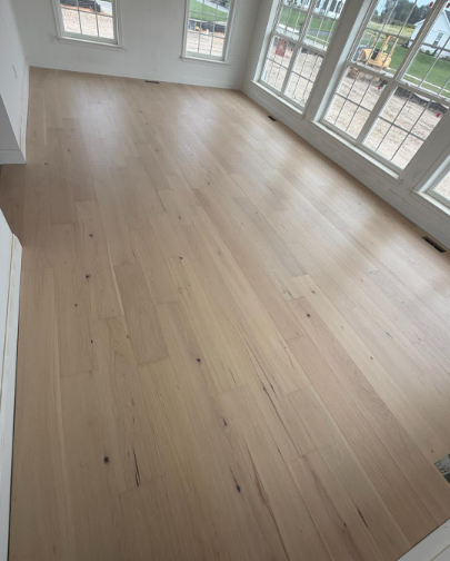 Bright empty room with light wood flooring and large glass doors/windows.