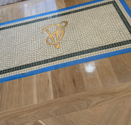 Decorative mosaic floor medallion with blue border on a wood floor