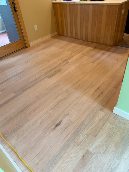 Empty room with light wood flooring and a wooden counter at the back