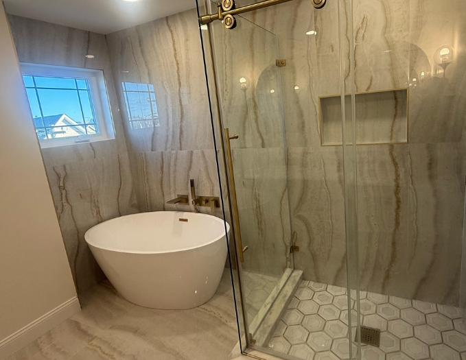 Modern bathroom with a freestanding tub, glass shower, and marble-patterned walls and floor.