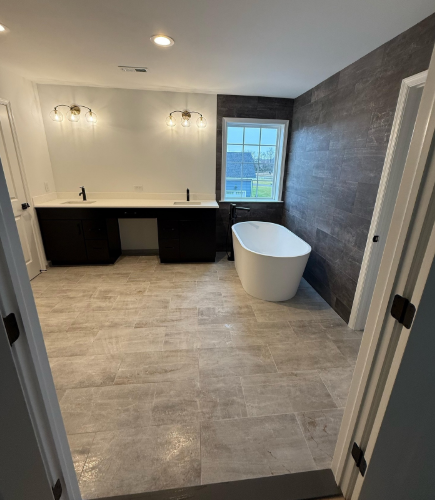 Modern bathroom with double vanity, freestanding tub, gray tile floor, and window