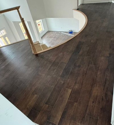 Dark wood flooring in a curved upstairs landing with a staircase opening and white walls