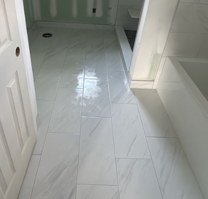 White tiled bathroom with shower and bathtub, showing a clean floor and doorway.