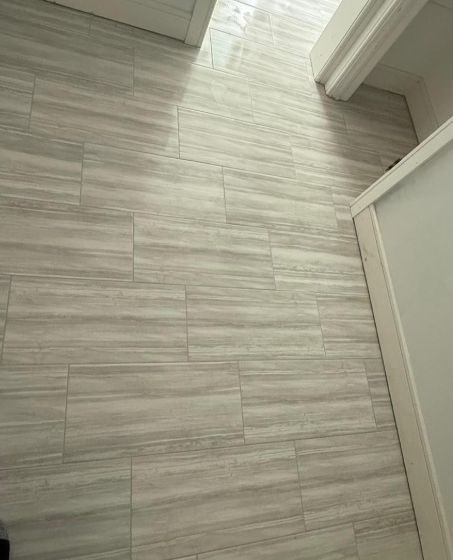 Light gray wood-look tile floor in a hallway with white door frames and a partially open door