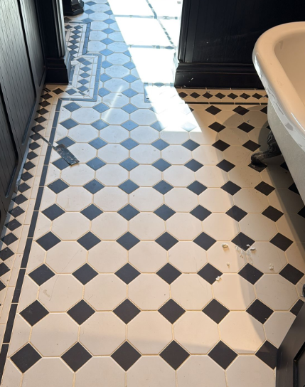 Black-and-white diamond-patterned tile floor in a bathroom with sunlight streaming in