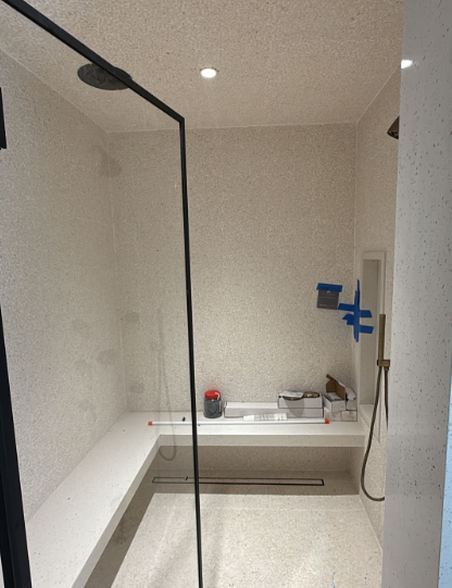Modern bathroom with walk-in shower, white tub, and black shower frame; blue painter’s tape on the wall