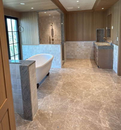 Luxury bathroom with marble tile, freestanding tub, walk-in shower, and vanity under wood-paneled walls
