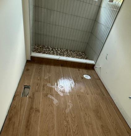 Empty hallway with wood flooring, white walls, and a fallen ceiling panel near the far end.