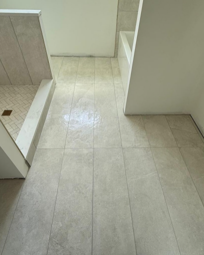 Light beige tiled hallway with a step down and white walls, leading into an adjacent room.