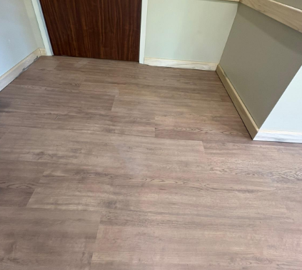 Empty room with light wood flooring and white walls, viewed toward a closed wooden door.