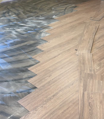 Blue-gray flooring transitions into light wood herringbone planks in a room under renovation.